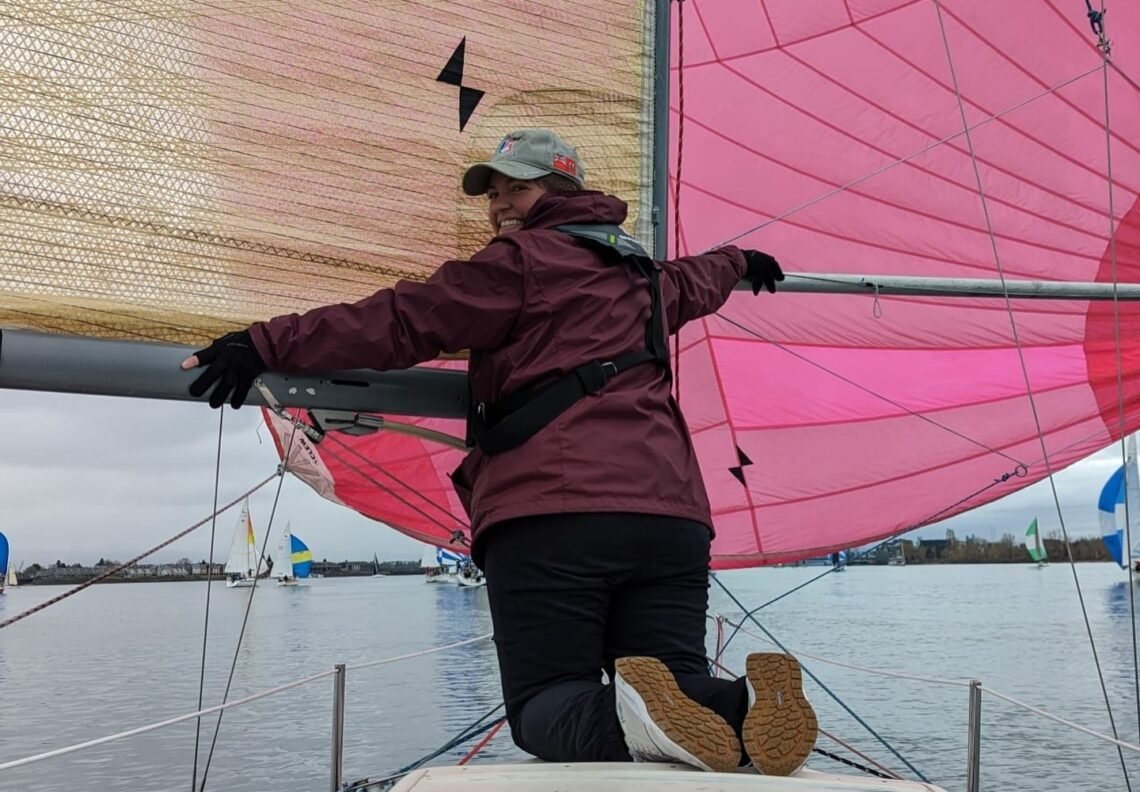 Sarah supporting the boom and spinnaker pole on a downwind leg.