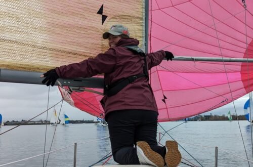 Sarah supporting the boom and spinnaker pole on a downwind leg.